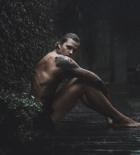 tattooed man posing in the rain